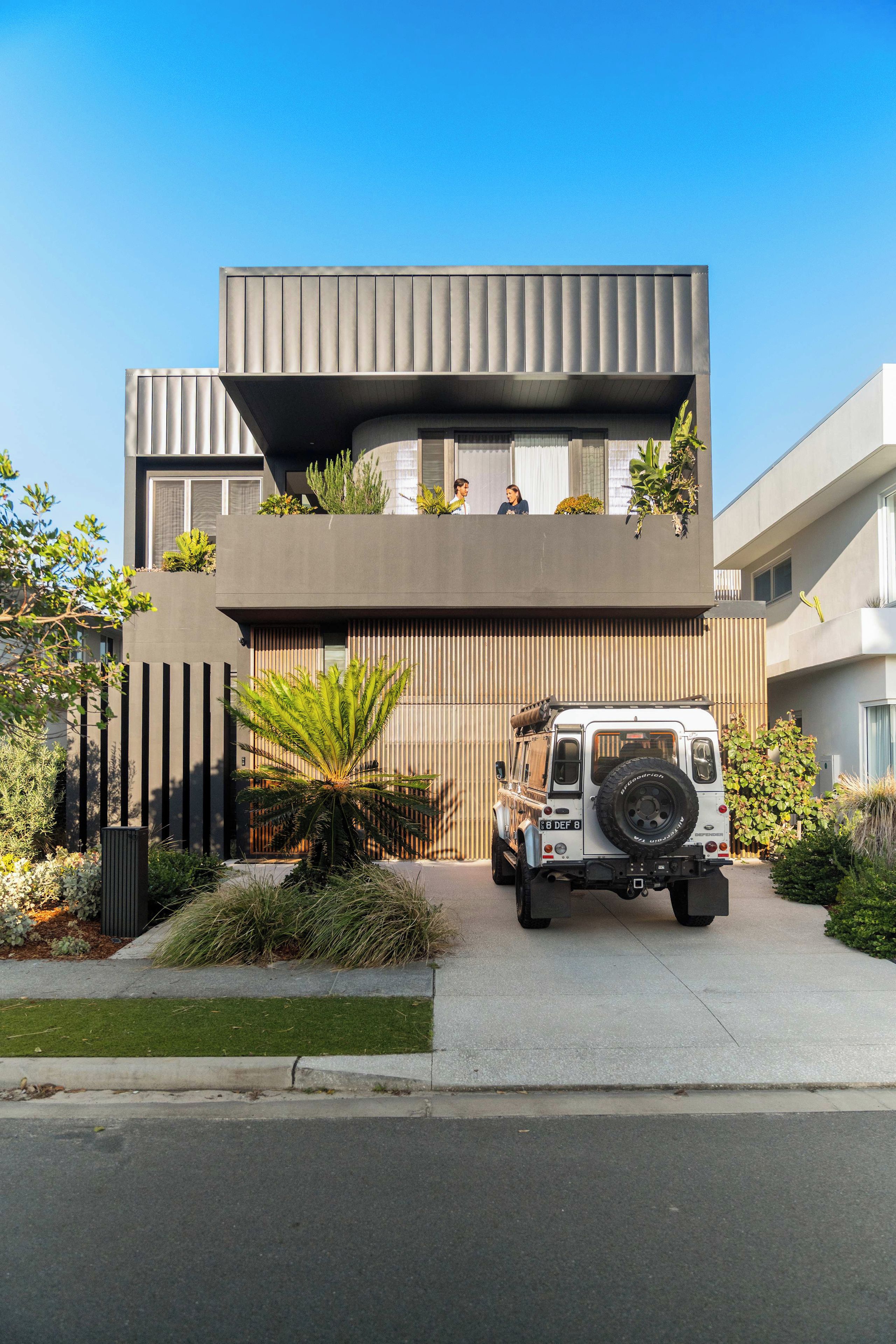 Un edificio moderno con tejado plano, un garaje y un vehículo estacionado.