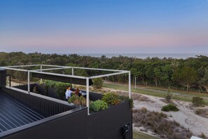 Una terraza en la azotea con vistas al mar, rodeada de vegetación.