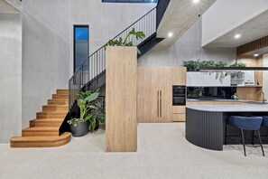 Una cocina moderna con una isla central, una escalera con escalones de madera y plantas en macetas.