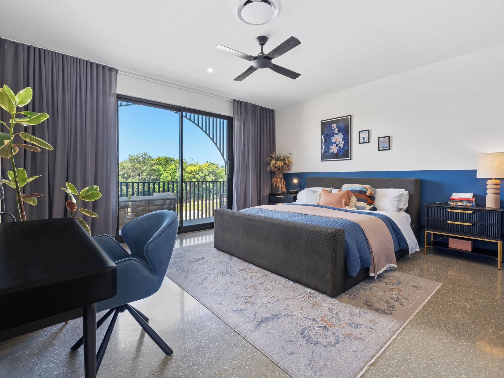 Una habitación de hotel moderna con una cama grande, un escritorio, una silla y un balcón con vistas.