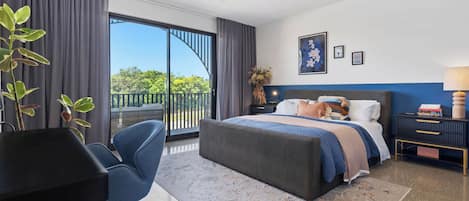 Una habitación de hotel moderna con una cama grande, un escritorio, una silla y un balcón con vistas.