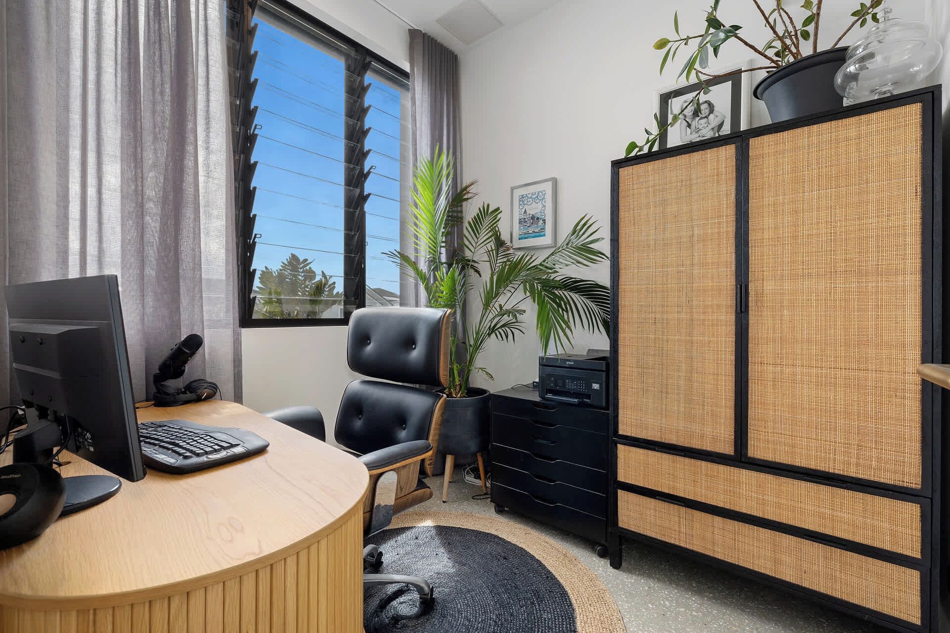 A modern office with a computer, a chair, a desk, a cabinet, and a window with curtains.