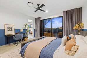 A hotel room with a bed, a desk, a chair, a ceiling fan, and a view of the outdoors. - Black on Black Wattle - Beachfront, Rooftop, Pool (Casuarina)
