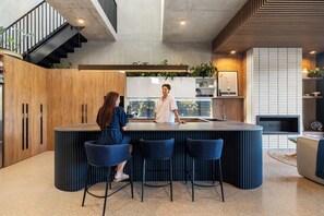 Una cocina moderna con una isla central, taburetes de bar y una escalera.