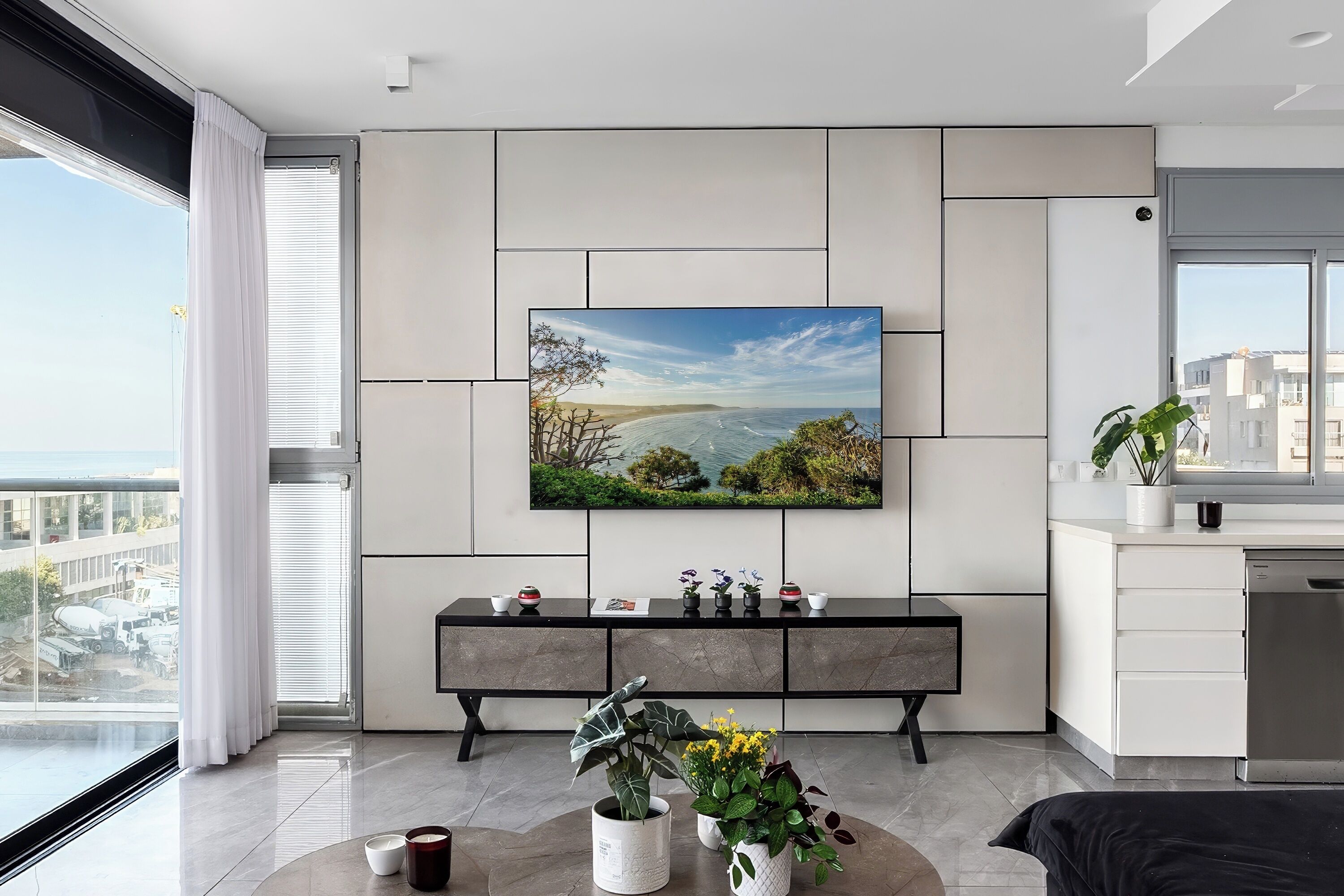 Eine moderne Küche mit großem Fenster, einem Wand-Flachbildfernseher und einem Essbereich mit einer Bank.