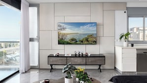 Een moderne keuken met een groot raam, een flatscreen televisie aan de muur en een eethoek met een bank.