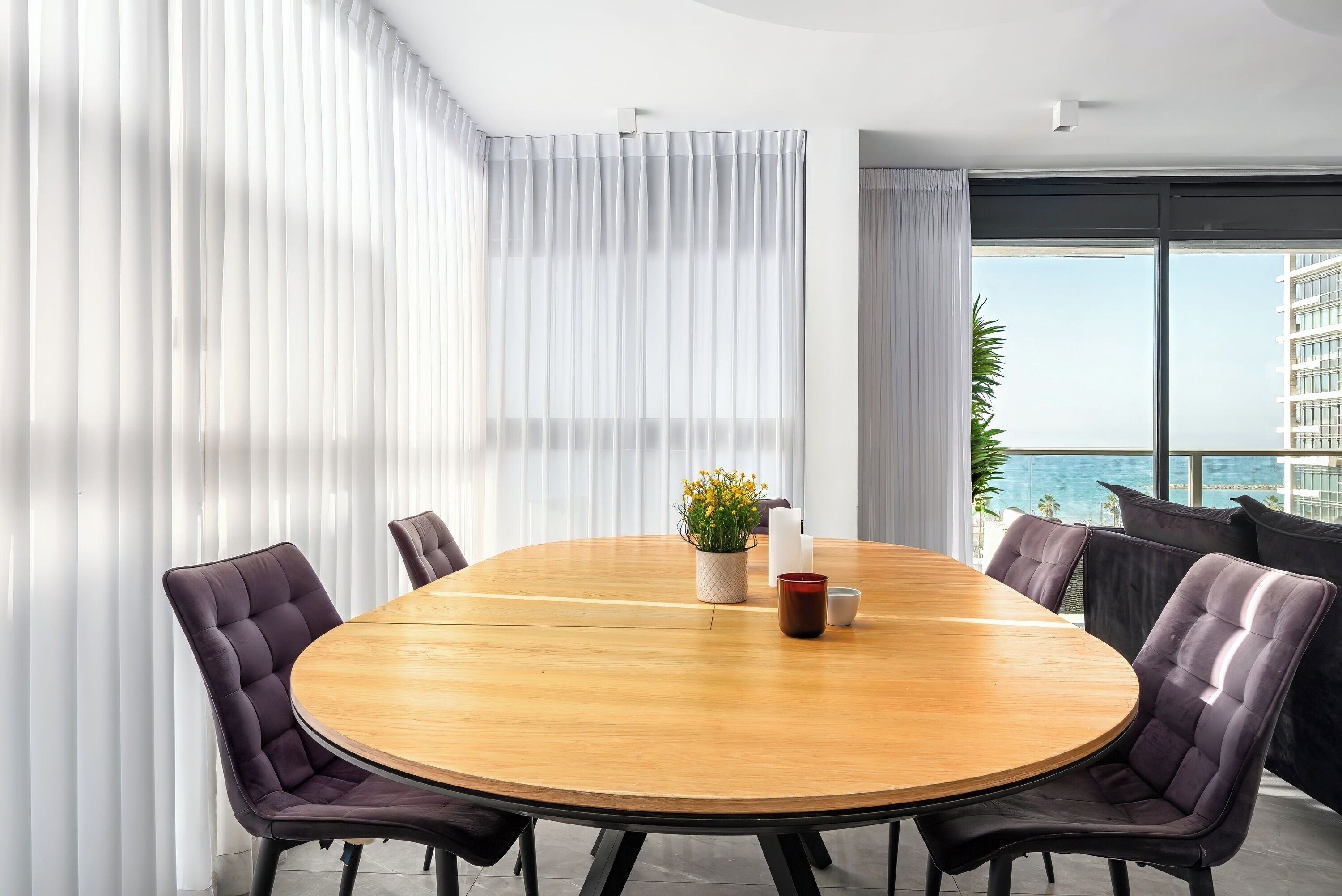 Ein moderner Konferenzraum mit einem runden Holztisch, sechs gepolsterten Stühlen und einem Blumentopf.