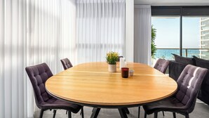 Een moderne vergaderruimte met een ronde houten tafel, zes gestoffeerde stoelen en een potplant.