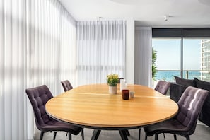 Une salle de conférence moderne avec une table ronde en bois, six chaises rembourrées et une plante en pot.