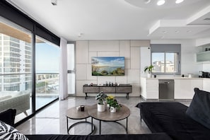Un appartement moderne comprenant un espace de vie, une cuisine et de grandes fenêtres offrant une vue sur la ville.