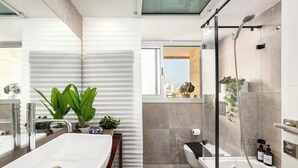 Een moderne badkamer met een groot wastafel, douche en toilet. Er staan planten en toiletartikelen op het aanrecht.