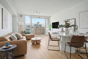 A modern apartment with a living room, dining area, and kitchen. There is a large window providing a view of the city. - Double Bay Delight with Parking - NEW (Double Bay)