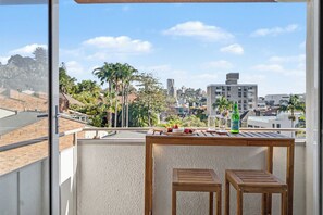 Ein Balkon mit einem Holztisch, zwei Stühlen und einer Flasche Alkohol.