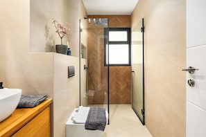 Une salle de bain moderne avec une douche à parois de verre, un lavabo blanc et un meuble-lavabo en bois.