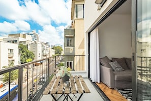 Un balcon avec une table en bois, un pot de fleurs et un canapé avec des coussins.