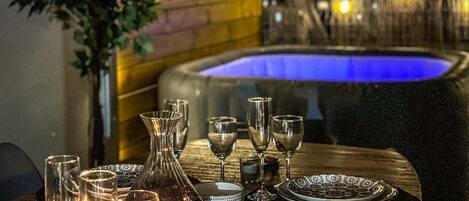 A dining table set for a meal with glasses, plates, and a vase.
