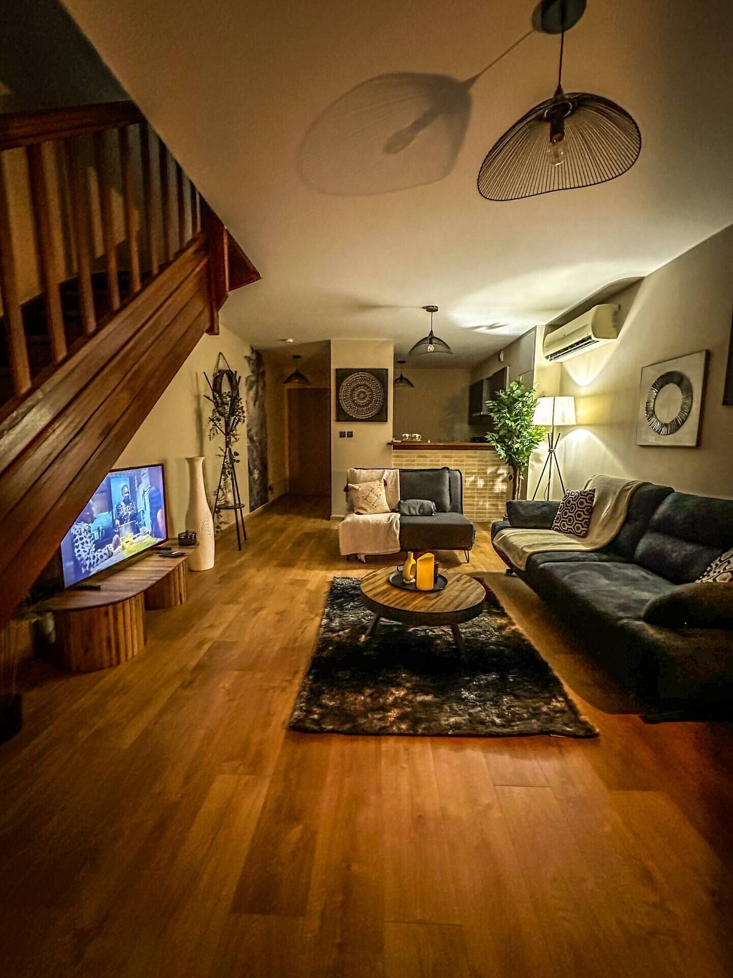 Ein Wohnzimmer mit einer Holztreppe, einem Fernseher, einem Couchtisch und einem Sofa.