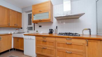 A modern kitchen with wooden cabinets, a dishwasher, a stove, and a window above the sink.