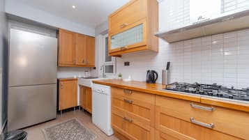 A modern kitchen with wooden cabinets, a stainless steel refrigerator, a dishwasher, and a gas stove.