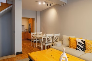 A modern living room with a wooden dining table, white chairs, and a sofa with yellow cushions. - Spacious 4BR Private Townhouse with Exclusive Terrace (İstanbul)