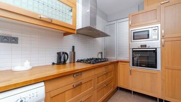 Een moderne keuken met houten kastjes, een ingebouwde magnetron, oven en gasfornuis.
