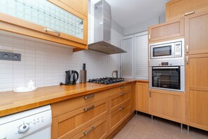 A modern kitchen with wooden cabinets, a built-in microwave, oven, and a gas stove.
