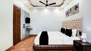 A bedroom with a bed, a ceiling fan, a mounted TV, and artwork on the wall. - Classic Aspiring Inn (Kolkata)