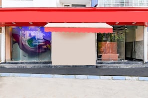 Una fachada con toldo rojo, grandes ventanales y una entrada visible.