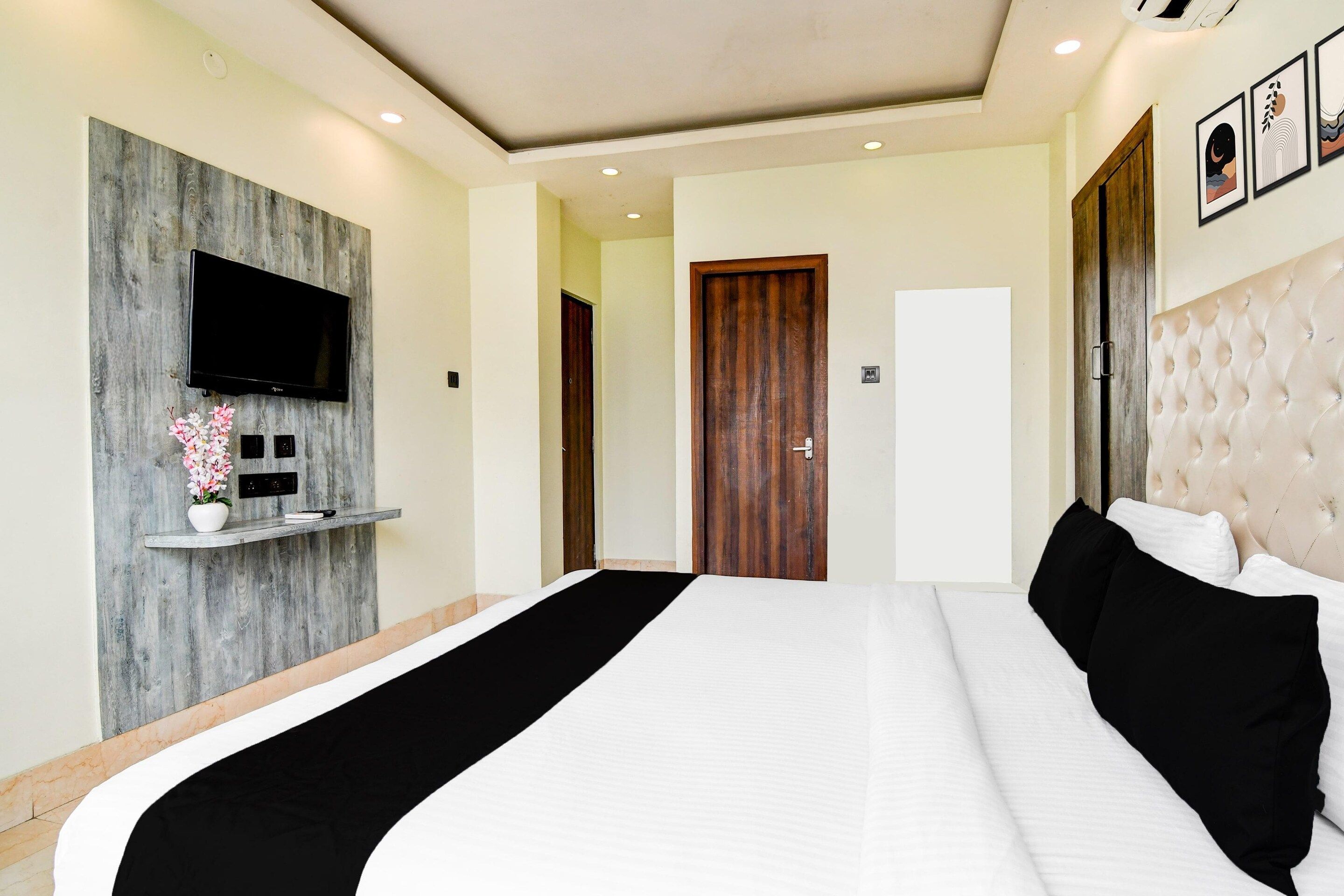 Ein Hotelzimmer mit einem großen Bett, einem Wand-Fernseher, einer Wandvertäfelung aus Holz und einer Tür zu einem weiteren Raum.