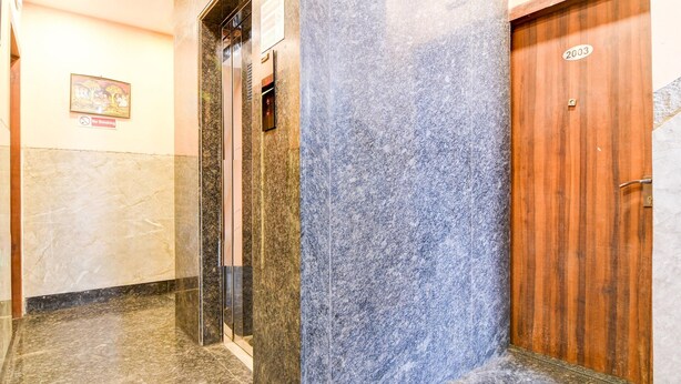 A hallway with a wooden door, a marble wall, and a no-smoking sign. - Classic Aspiring Inn (Kolkata)