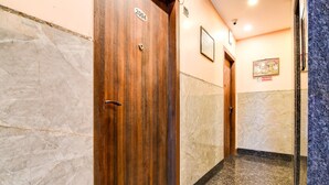 A hallway with wooden doors, marble walls, and a no-smoking sign. - Classic Aspiring Inn (Kolkata)