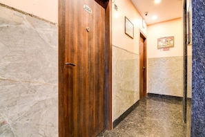 Un pasillo con puertas de madera, paredes de mármol y un cartel de prohibido fumar.