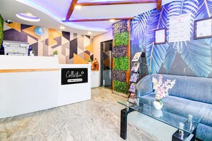 A reception area with a modern design, including a reception desk, a sofa, and a wall with vertical gardens.