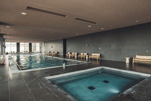 A large indoor swimming pool with a separate smaller pool, lounge chairs, and a bench along the walls. - AC, 2 bedrooms, 2 bathrooms, fully equipped kitchen, high speed internet, comfy beds. (Centro)