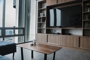 A modern living room with a large flat-screen TV, wooden shelving, and a city view. - AC, 2 bedrooms, 2 bathrooms, fully equipped kitchen, high speed internet, comfy beds. (Centro)
