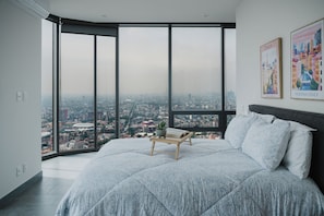 A bedroom with a large bed, a bedside table with a book and a plant, and a city view through floor-to-ceiling windows. - 2 bedrooms, 2 bathrooms, fully equipped kitchen, high speed internet, comfy beds. (Centro)