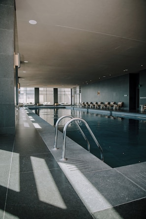 An indoor swimming pool with a metal ladder, tiled floor, and lounge chairs along the walls. - AC, 2 bedrooms, 2 bathrooms, fully equipped kitchen, high speed internet, comfy beds. (Centro)