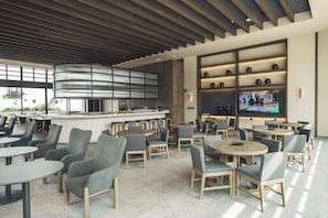 A modern indoor dining area with round tables and chairs, a bar counter, and a large screen displaying a sports event. - 2 bedrooms, 2 bathrooms, fully equipped kitchen, high speed internet, comfy beds. (Centro)