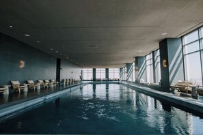 Piscina interna con lettini e vista sulla città.