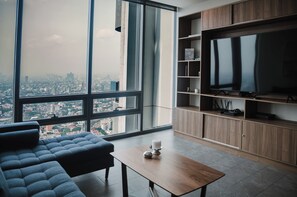 A modern living room with a large window, a sofa, a coffee table, and a TV on a wooden cabinet. - AC, 2 bedrooms, 2 bathrooms, fully equipped kitchen, high speed internet, comfy beds. (Centro)