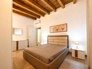 A bedroom with a bed, bedside tables, a door, a painting, and a wooden ceiling. - The Sainte Cécile Residence (Palermo)