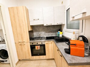 Eine kompakte Küche mit Herd, Backofen, Spüle und einer Kaffeemaschine.