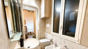 Un bany modern amb un mirall gran, un lavabo, un vàter i una finestra.