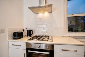 Et køkken med gaskogeplade, ovn og en brødrister på bordpladen.