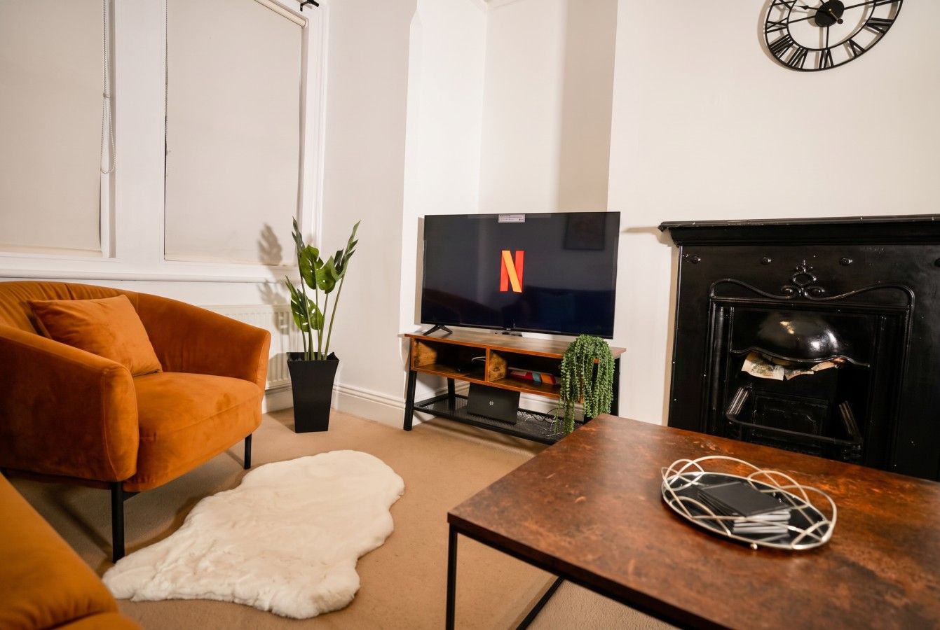 Un salon comprenant un canapé, une table basse, un téléviseur, une cheminée et une horloge murale.