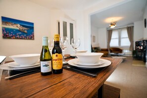 A dining table with two wine bottles, a bowl, and a wine glass.
