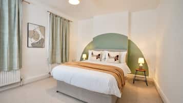 Ein Schlafzimmer mit Bett, Nachttisch, Lampe, Heizkörper und einem Wandbild.