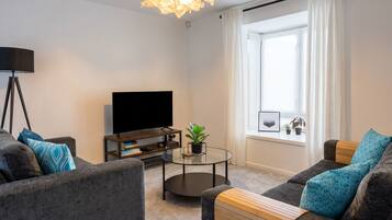 Lounge with twin sofas and TV set around a glass coffee table in the bay window.