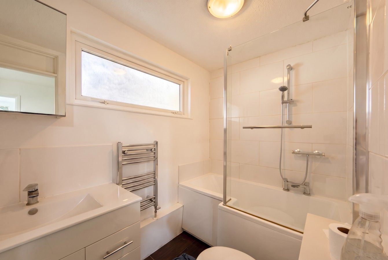 Bathroom with bathtub, shower screen and heated towel rail.
