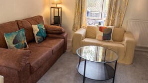 A living room with a brown sofa, beige sofa, and a glass coffee table. - Pet-Friendly 3-Bed House with Garden · Sleeps 6 in Headington, Oxford (Headington)